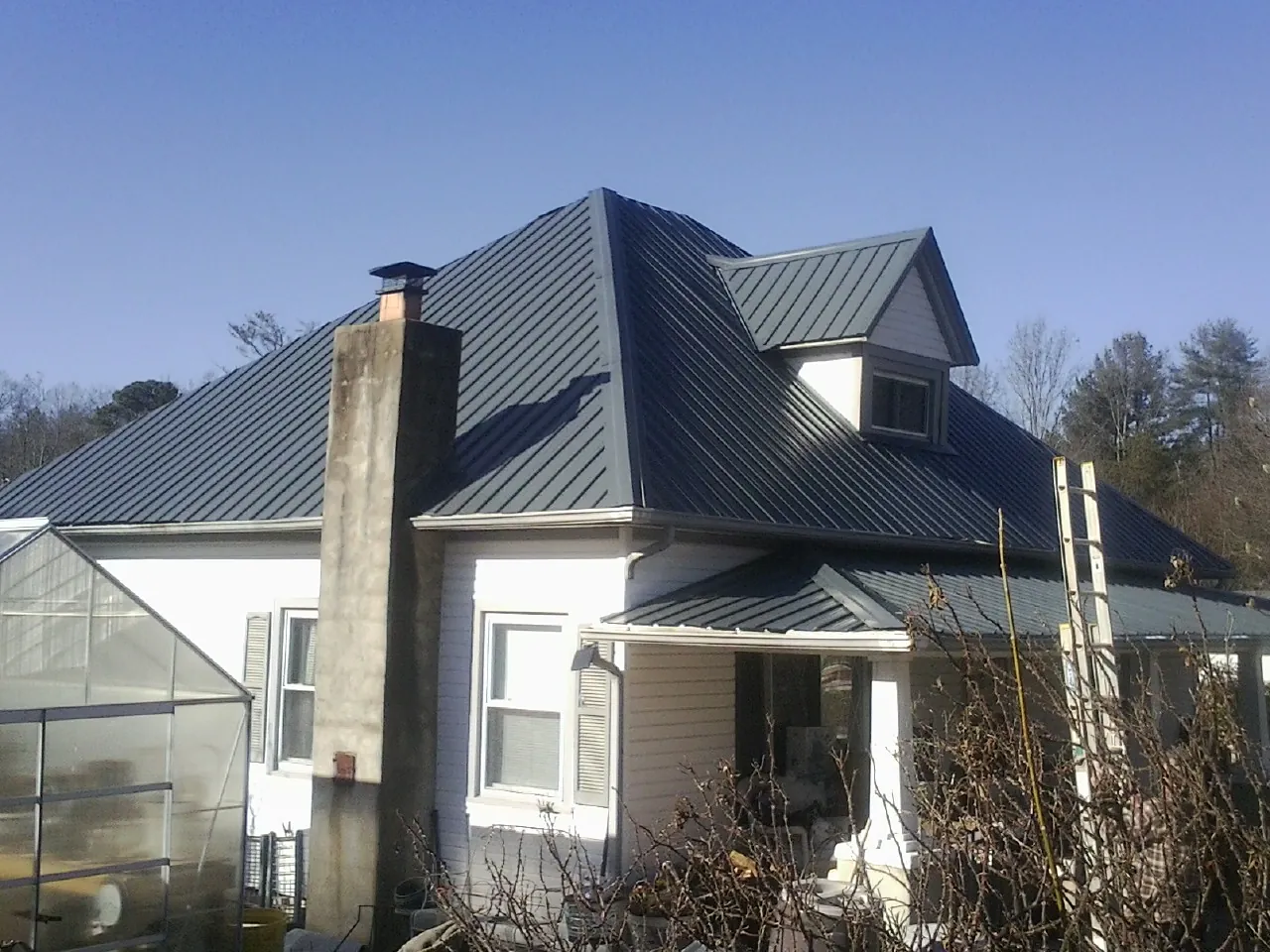 Dark blue standing seam metal roof on a white farmhouse with dormer — Slate & Tile Roof Repair by Roofing Brothers in West Nottingham