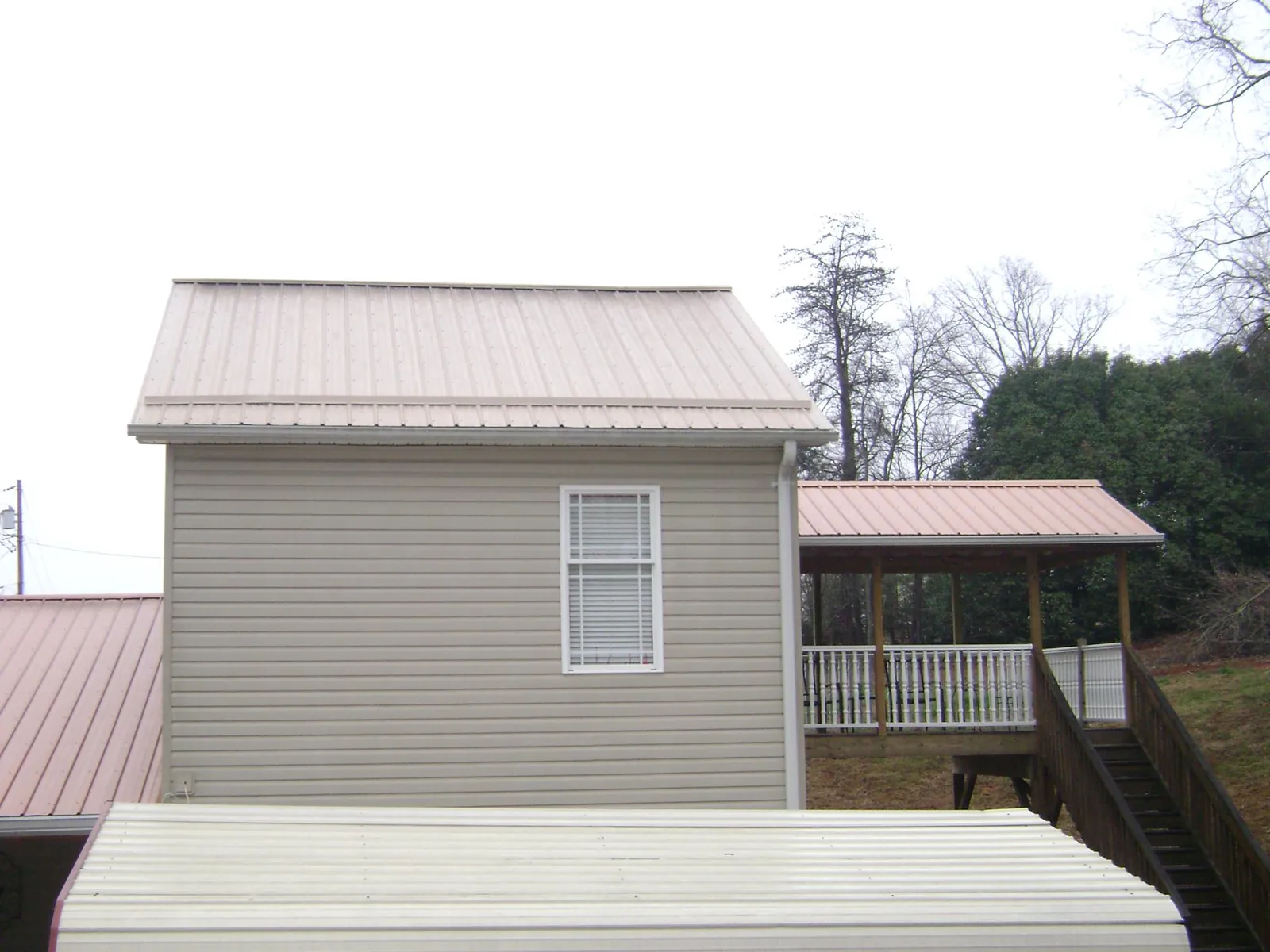 Tan metal roofs on a two story addition and attached porch, from a Roof Replacement job in West Nottingham