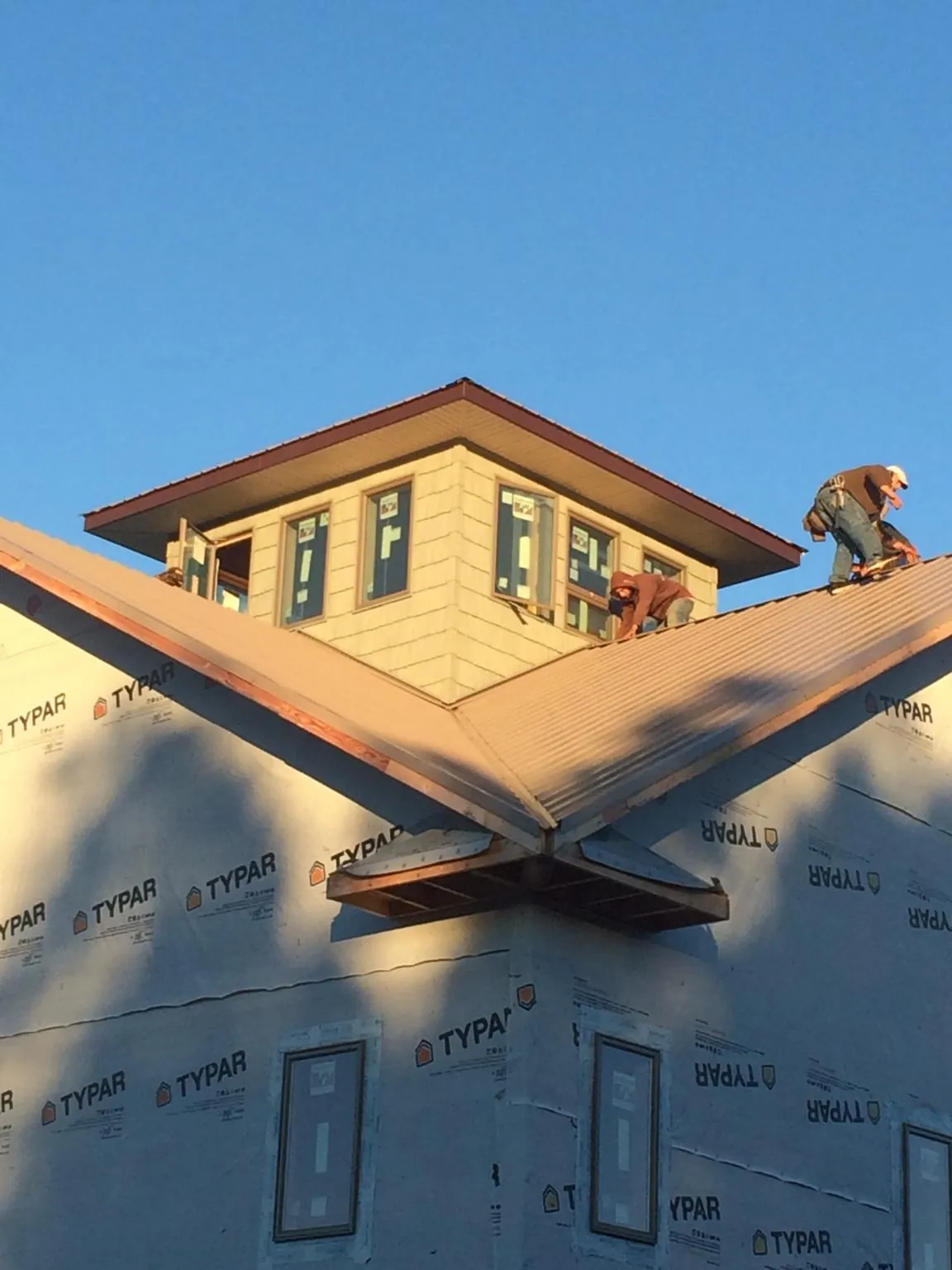 Roofers working around a rooftop cupola on a new metal roof at sunset — Roof Waterproofing in West Nottingham by Roofing Brothers